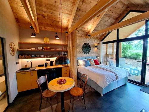 a bedroom with a bed and a table and a kitchen at Hotel Kouty - Lesní Apartmány in Ledeč nad Sázavou