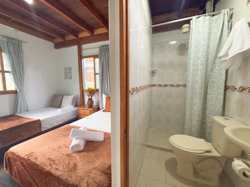 een badkamer met een bed, een douche en een toilet bij Las Casas de Tomate in Guatapé