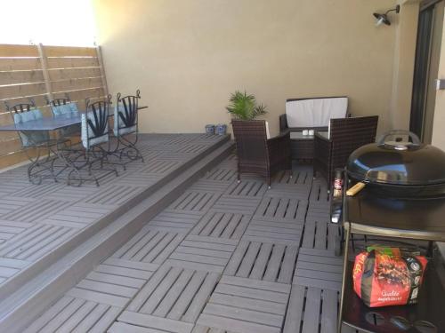 un patio avec des chaises, une table et un grill dans l'établissement Un petit cottage en Provence, à Maillane