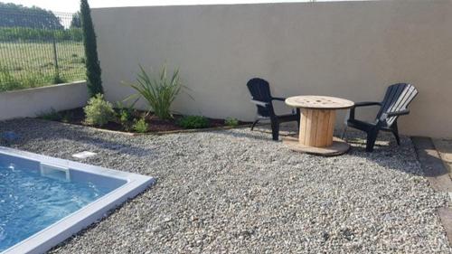 une terrasse avec 2 chaises, une table et une piscine dans l'établissement Un petit cottage en Provence, à Maillane
