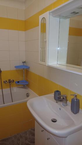 a bathroom with a sink and a mirror and a tub at Nelli apartman free parking in Šamorín