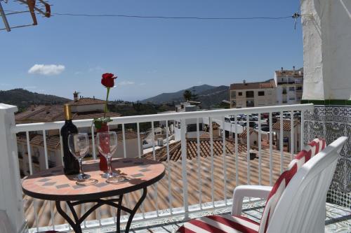 un tavolo con una bottiglia di vino e due bicchieri sul balcone di Casa Berrincha a Cómpeta