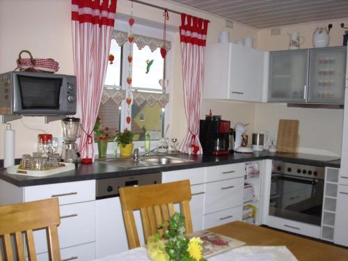 a kitchen with white cabinets and red curtains at Wohnung In Oberwaldbach Mit Garten Und Grill in Burtenbach