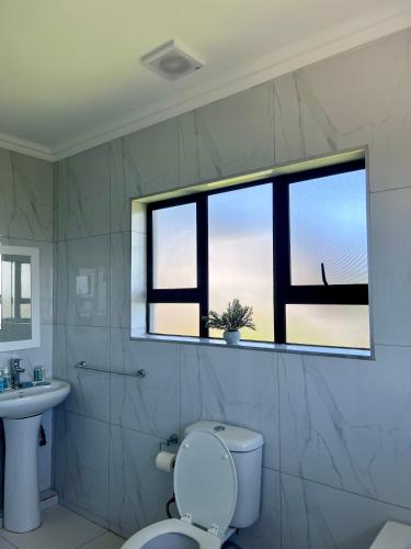 a bathroom with a toilet and a sink and a window at Montrose BnB in Margate