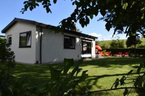 een klein wit huis in een grasveld bij Kleines Haus Mit Garten, Direkt Hinter Dem Deich in Baarland