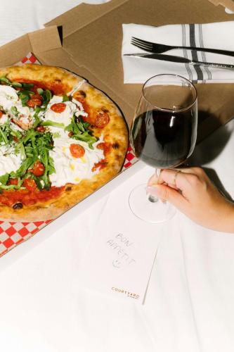 a person holding a glass of wine next to a pizza at Courtyard by Marriott Montreal Laval in Laval