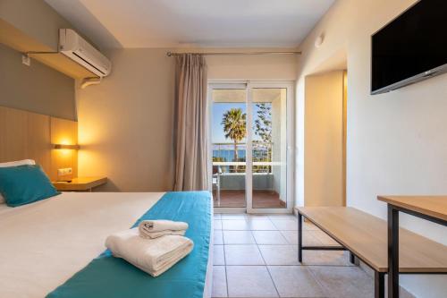 a hotel room with a bed and a desk and a window at Kos City Sunstone Hotel in Kos