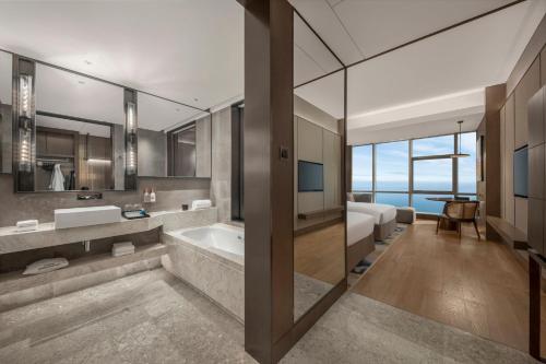 a bathroom with a tub and a sink and a bedroom at Crowne Plaza Beihai Silver Beach by IHG in Beihai