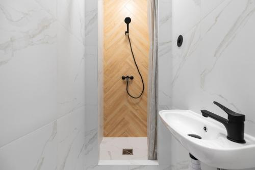 a white bathroom with a shower and a sink at Najtańsze noclegi Piłsudskiego 93 in Łódź