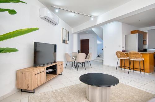 a living room with a tv and a table at Pafilia Gardens 6 in Paphos