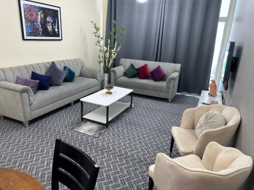 a living room with two couches and a table and chairs at sweet home 2 BHK apartment in Ajman