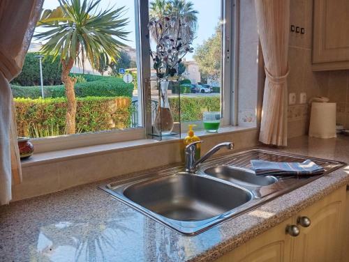 a kitchen sink in front of a window with a palm tree at Villa Oasis Parque BY SWEET HOME in Portimão