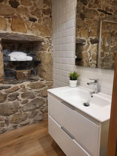 a bathroom with a sink and a stone wall at Casa Laxeira in Tabagón