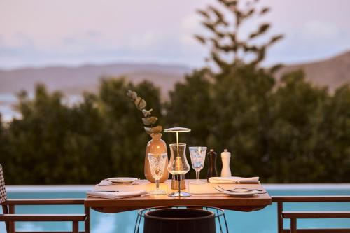 a table with wine glasses and a vase on it at Aquila Elounda Village Resort, Suites & Spa in Elounda