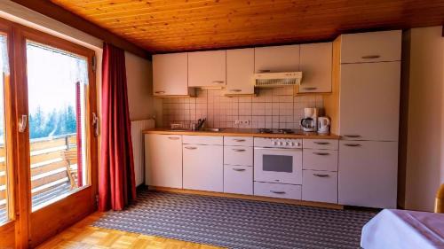 cocina con electrodomésticos blancos y ventana grande en Ferienwohnung Haus Kipfen In Sibratsgfäll, en Sibratsgfäll