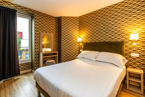 une chambre avec un grand lit et une fenêtre dans l'établissement Denfert-Montparnasse, à Paris