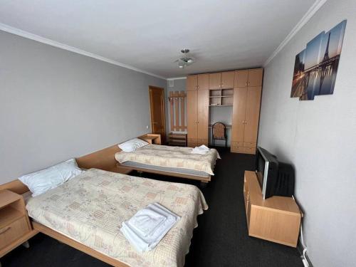 a room with two beds and a flat screen tv at Tumar Apart Hotel in Karagandy
