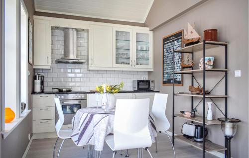a kitchen with white cabinets and a table and chairs at Amazing Home In Skjoldastraumen in Skjoldastraumen
