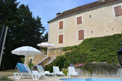- un groupe de chaises et un parasol à côté d'un bâtiment dans l'établissement Gîte AYMARE 12 personnes, au Vigan