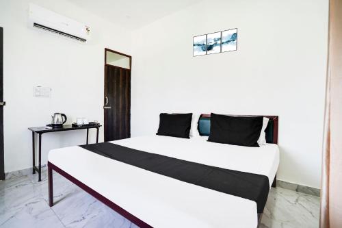 1 dormitorio con 1 cama blanca grande con almohadas negras en Hotel O The Moon, en Bareilly
