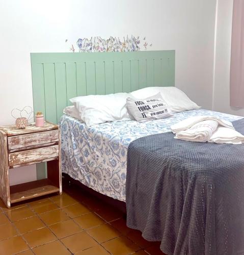 a bed with a green headboard next to a table at Apartamento Studio 201 in Juazeiro