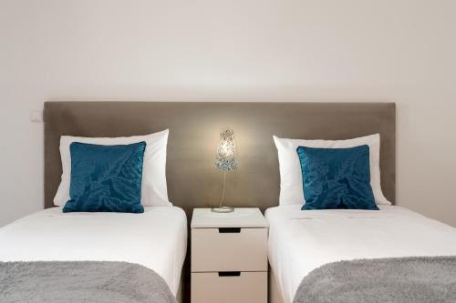 two beds with blue pillows in a bedroom at Caniço Golden by An Island Apart in Caniço
