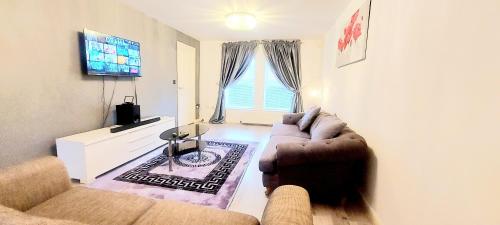 a living room with a couch and a television at Sunderland Villa Luxuria House and Apartment Accommodation - Free Double Private Parking in Sunderland