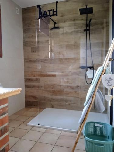 La salle de bains est pourvue d'une douche et d'un mur en bois. dans l'établissement Gite meublé avec étang en lisière de forêt., à Les Grandes Prouillères