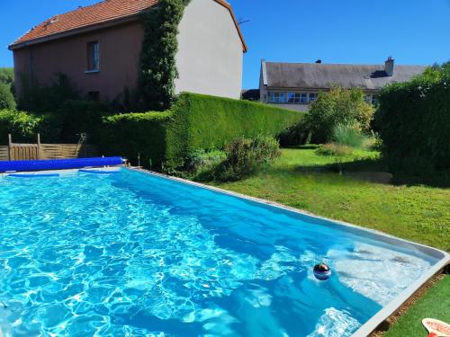 une piscine avec de l'eau bleue dans une cour dans l'établissement La Clouterie - Face au ruisseau piscine privée, à Remilly-Aillicourt
