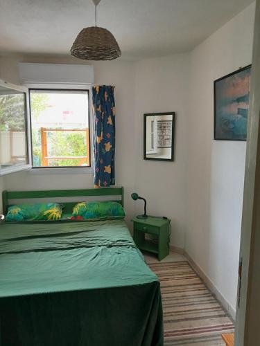 une chambre avec un lit vert et une fenêtre dans l'établissement Les Goélettes - Vue mer et montagne plage à 100m, à Saint-Cyprien