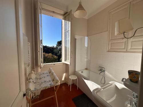 une salle de bain avec une baignoire, un lavabo et une fenêtre dans l'établissement Bastide provençale avec piscine, à Marseille