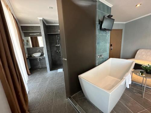 a bathroom with a bath tub and a bedroom at Regina Maria Spa Design Hotel in Balchik