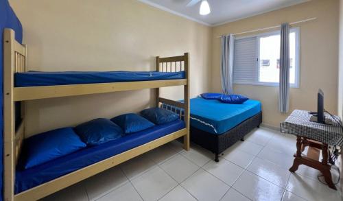 deux lits superposés avec des oreillers bleus dans une chambre dans l'établissement Cantinho do Churrasco - Varanda Gourmet a 60 mts praia, à Praia Grande