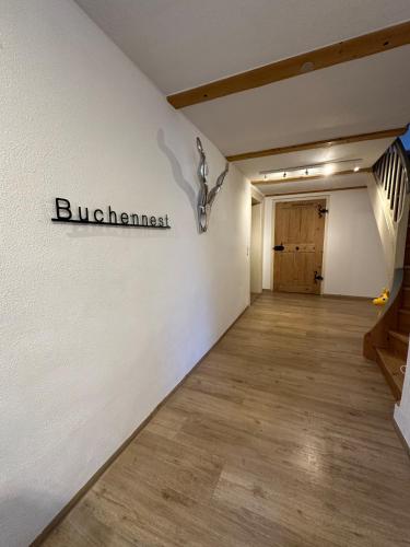 a hallway with a white wall with a sign on it at Buchennest in Halblech