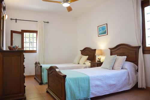 ein Schlafzimmer mit zwei Betten und einem Deckenventilator in der Unterkunft Charming Traditional Sea View Home in Es Cana