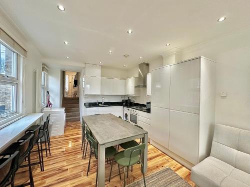 a kitchen with white cabinets and a table and chairs at Clapham apartment in London