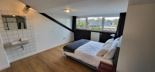 a bedroom with a bed and a sink and a window at Landhuis de heibloem in Heythuysen