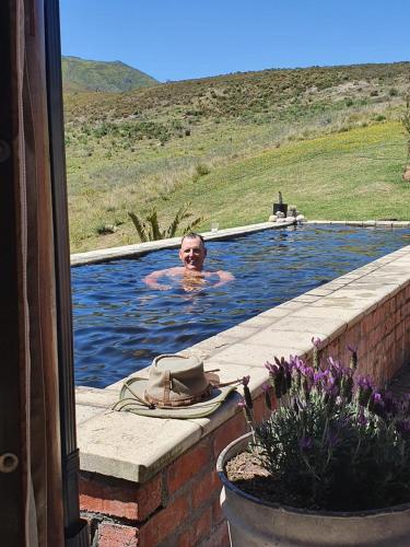 a man is in a swimming pool in at Helpmekaar Farm in Kareedouw