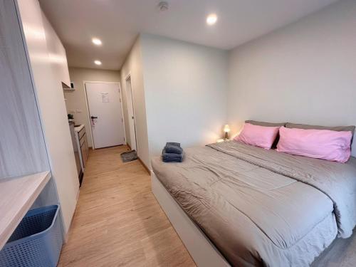 a small bedroom with a large bed with pink pillows at AVALYN Room Plus III - East Ville in Ban Hua Khao Sammuk