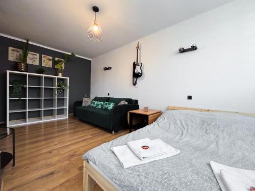 a bedroom with a bed and a couch and a guitar on the wall at Modern Living at Cieszyn Loft in Cieszyn