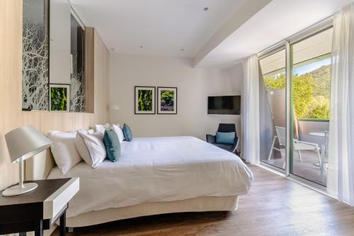 a white bedroom with a large bed and a table at Eau Thermale Avène l'hôtel in Avène