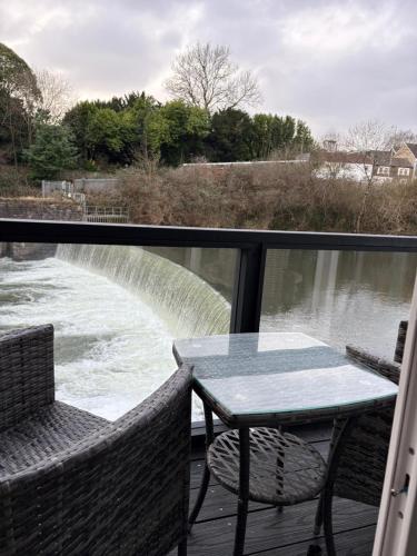 a table and chairs on a deck with a view of a river at Waters edge Pontypridd in Treforest