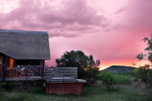 a house with a bench and a sunset in the background at Cradle Boutique Hotel in Lanseria