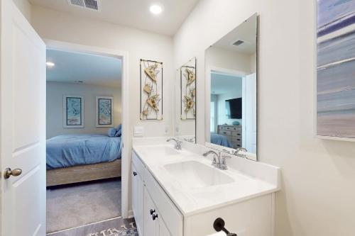 a bathroom with a sink and a mirror and a bed at Coastal Pines "2" in Ocean Isle Beach