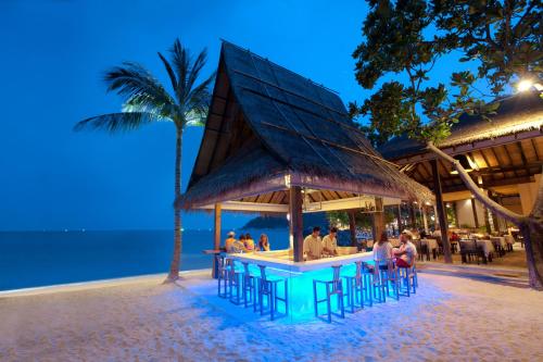 people sitting at a bar on the beach at night at Buri Rasa Village Phangan in Thong Nai Pan Noi