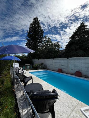 a swimming pool with chairs and an umbrella next to it at La Merlina in Merlo