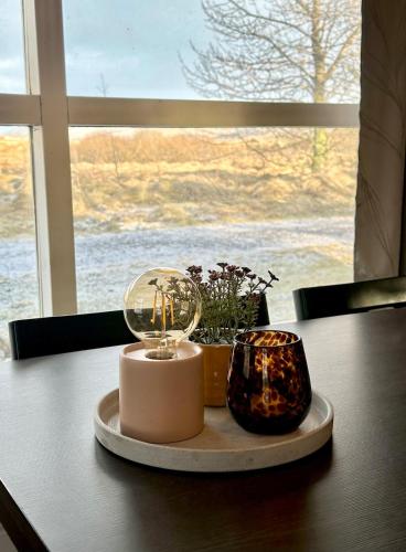 a table with two candles on a table with a window at Cozy, forest cabin #11 in Hvolsvöllur - Self check-in, outside jacuzzi! in Hvolsvöllur