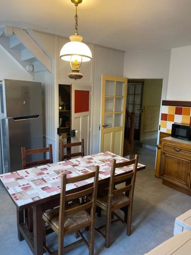 une cuisine avec une table avec des chaises et un réfrigérateur dans l'établissement Gîte des bords de Rance, à Langrolay