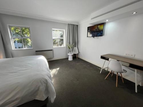 a white bedroom with a bed and a desk at Near CTICC Professional & Cosy Hotel Room in Cape Town