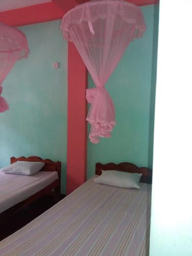 a bedroom with two beds and a pink curtain at Wellassa holly day in in Monaragala